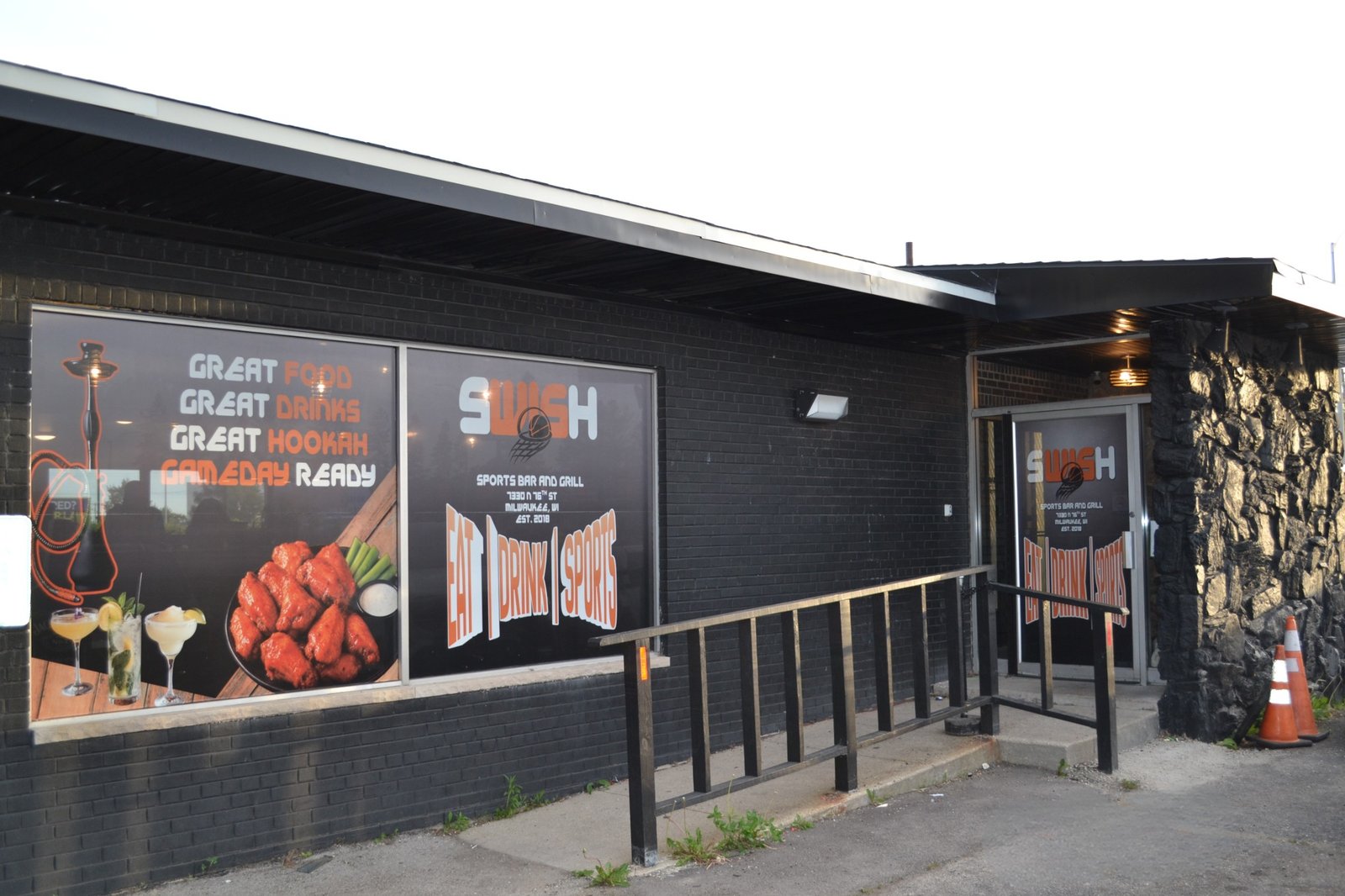 Completed Swish Sports Bar storefront with Craig’s orange-and-white window tint designs across the front windows and entrance.